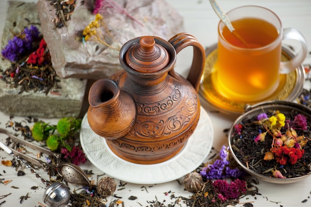 A teapot with the word kombucha on it sits on a white plate next to a cup of tea.