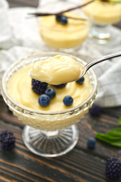 Teaspoon and dessert bowl with vanilla pudding on blurred background