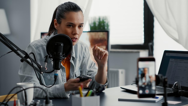 Photo tech enthusiast reviewing wireless mouse while presenting specifications to public. attractive social media star doing recommendation video for electronic peripheral while sitting at home studio desk.