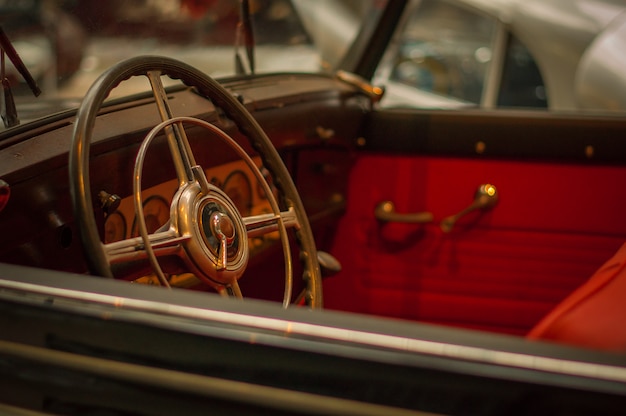 Technical Museum. Old retro car steering wheel, red interior.