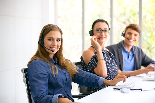 Technical support operator with headset working at laptop and computer