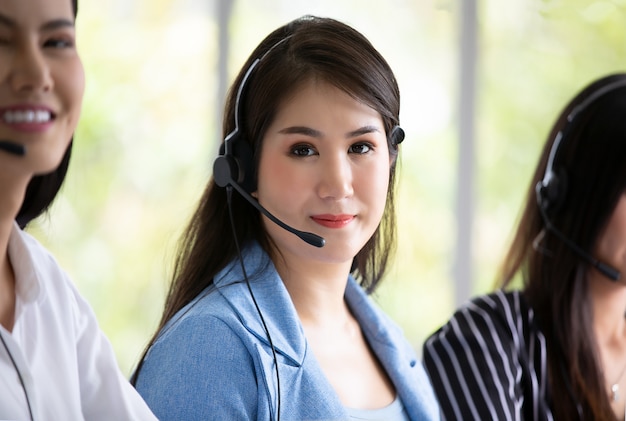 Photo technical support operator with headset working at laptop and computer