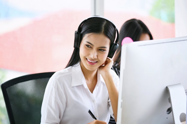 Technical support operator with headset working at laptop and computer