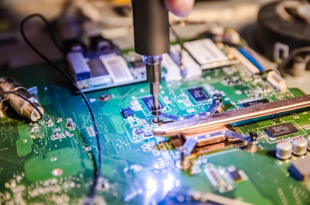 Technical support worker unspins the cover of the computer of the monoblock with a screwdriver with backlight