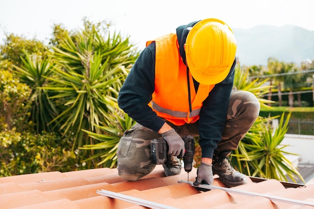 Technical worker works with drill on the roof of a house