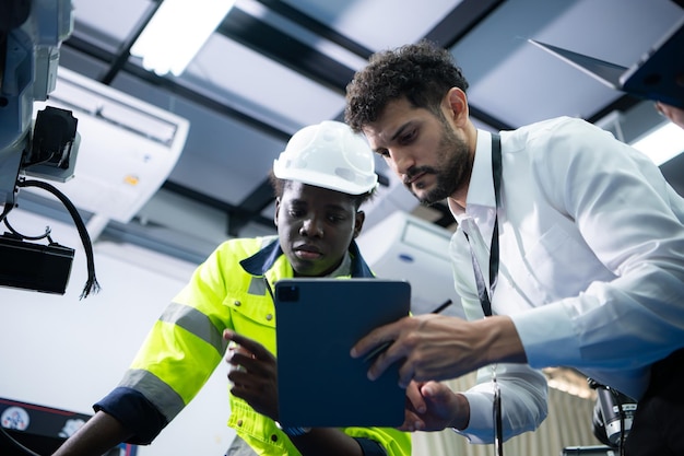 Foto technici introduceren industriële handrobots aan zakenlieden in de fabrieksindustrie