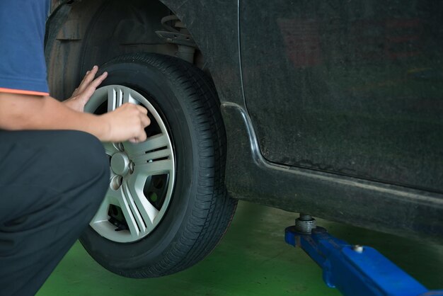 技術者がガレージでタイヤを交換しますメンテナンスフェーズによると車の問題をチェックします