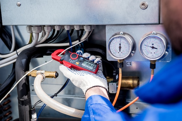 The technician checking power lines of the heat exchanger with current clamps