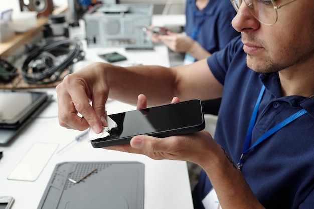 technician cleaning smartphone screen in repair shop setting