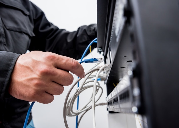 Tecnico che collega i cavi di rete agli switch. cavi di collegamento