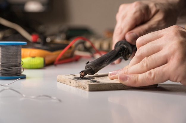 Technician electrician prepares rosin soldering iron to work