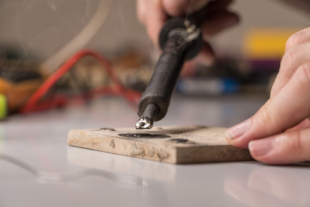 Technician electrician prepares rosin soldering iron to work