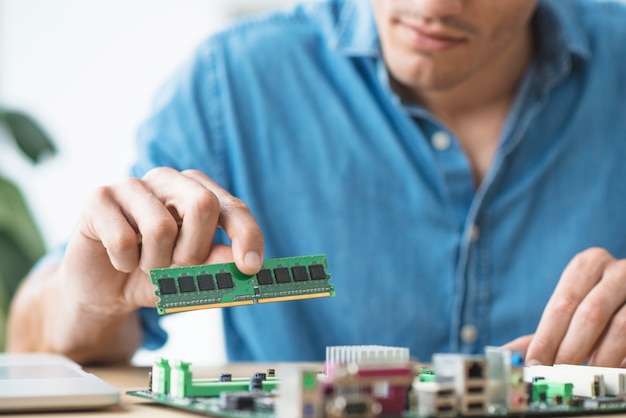 The technician fixing a RAM on the socket of the computer motherboard