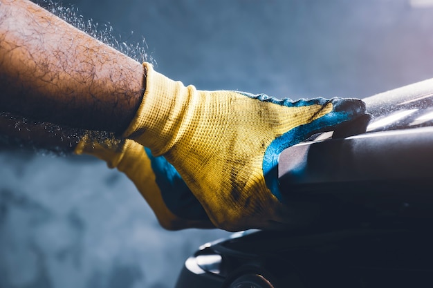 Photo technician hand pulling up car hood for maintenance in the repair garage