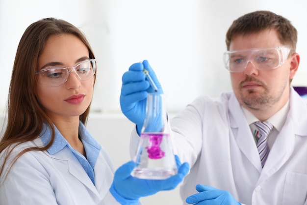 Technician hold in arms in protective gloves sample bottle