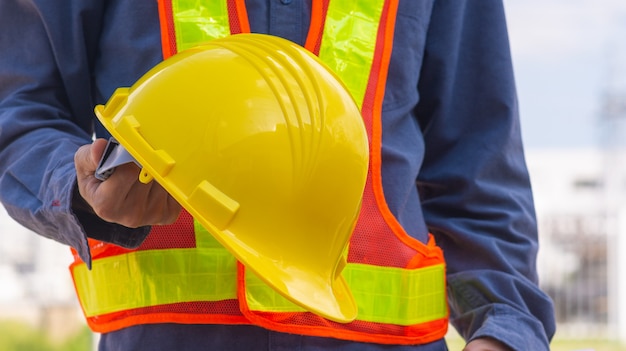 Tecnico che tiene il casco di sicurezza del casco giallo