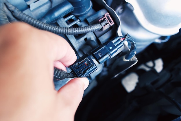 Technician inserting the alternator or generator plug of the car in the engine compartment automotive parts concept