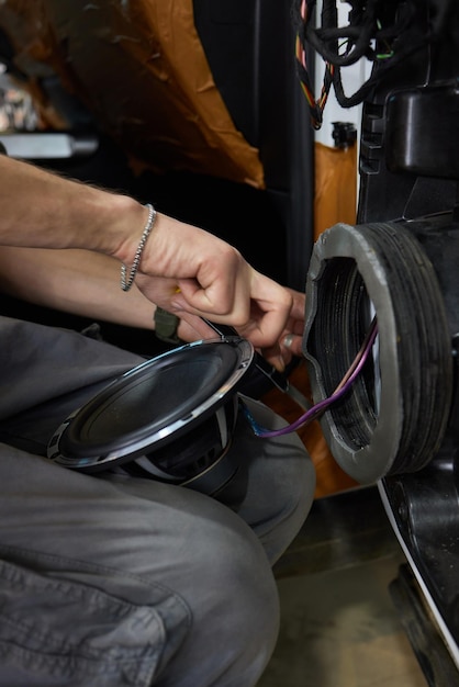 Foto tecnico che installa l'altoparlante dell'auto sulla porta dell'auto concetto di installazione dell'audio dell'auto