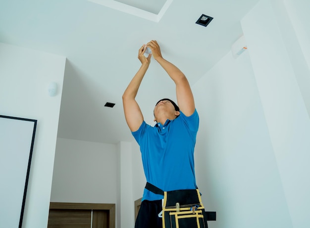 Technician installing fire safety detector in a modern apartment