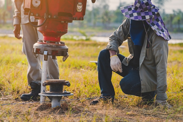 Technician installing ground screw for mounting structure of solar panel at solar farm