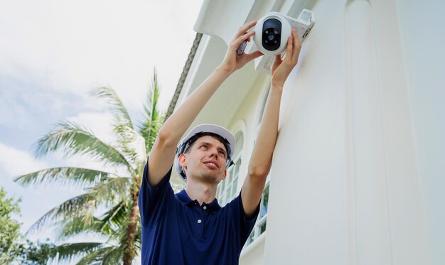 A technician installs a cctv camera on the facade of a residential building