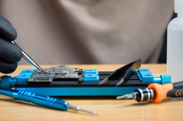 Photo technician is repairing smartphone motherboard circuit repair