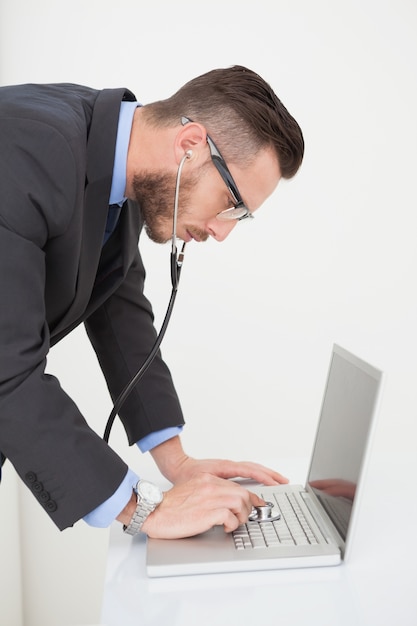 Technician listening to laptop with stethoscope