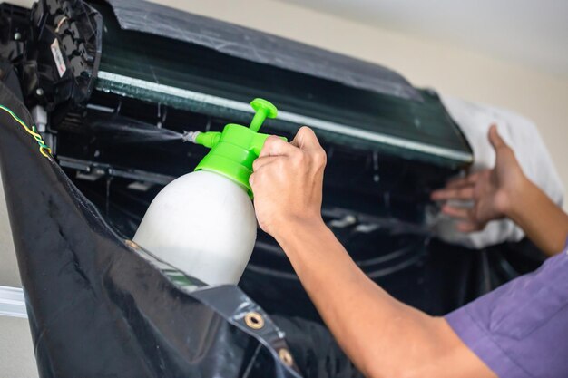 屋内でエアコンを掃除する技術者男性現代のエアコンを修理する修理工メンテナンスと修理の概念