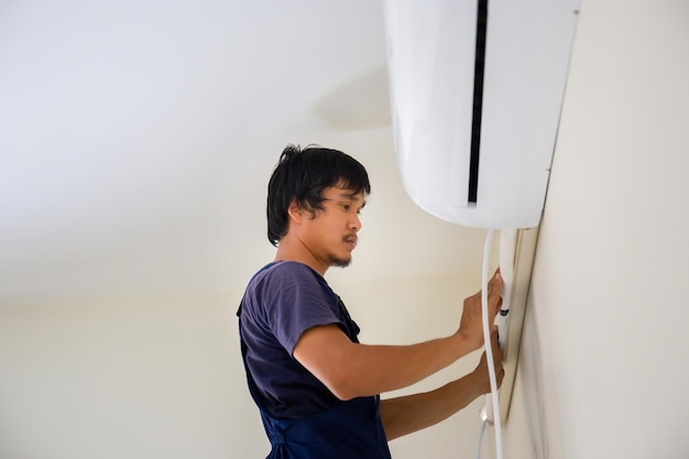 Technician man installing air conditioning in a client house Young repairman fixing air conditioner unit Maintenance and repairing concepts