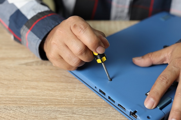 Technician man using screwdriver to fix or upgrade laptop computer