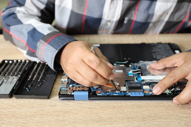 Technician man using screwdriver to fix or upgrade laptop computer