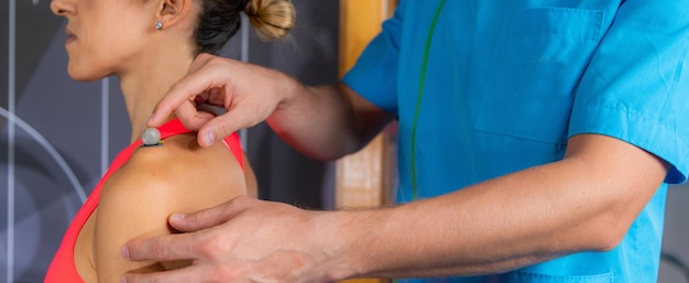 Technician placing markers on athletes shoulder preparing for 3d gait or movement analyses