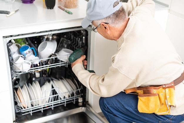 Техник или сантехник ремонтирует посудомоечную машину