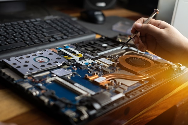 Technician repairing broken laptop notebook computer with screwdriver