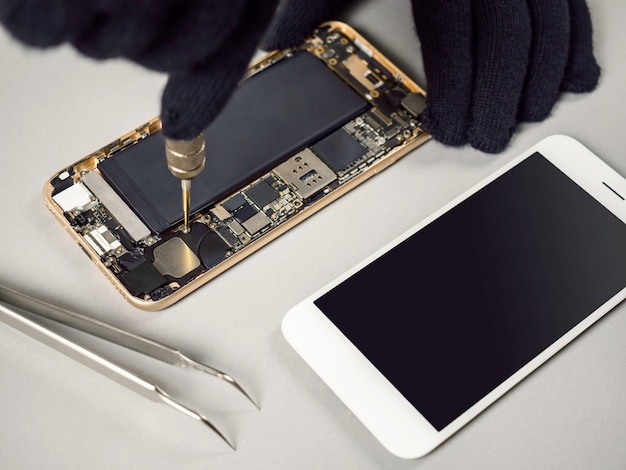 technician repairing broken smartphone on desk