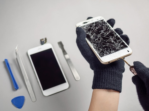 Photo technician repairing broken smartphone on desk