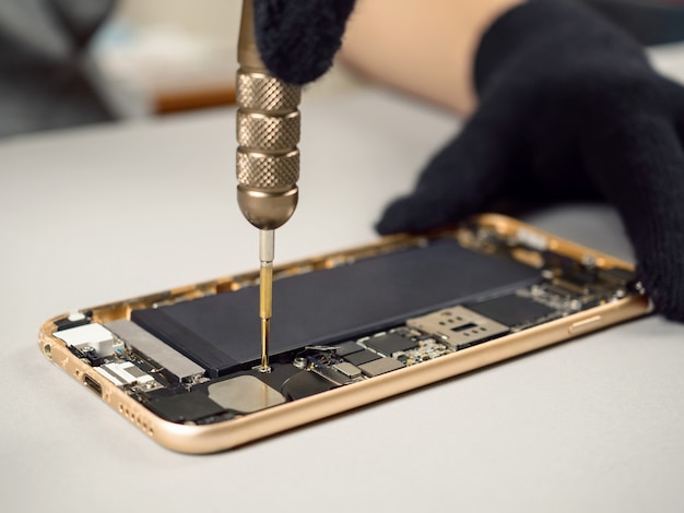 Photo technician repairing broken smartphone on desk