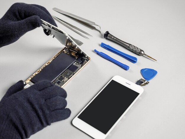 Photo technician repairing broken smartphone on desk