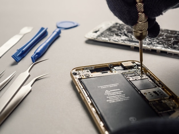 Technician repairing broken smartphone on desk