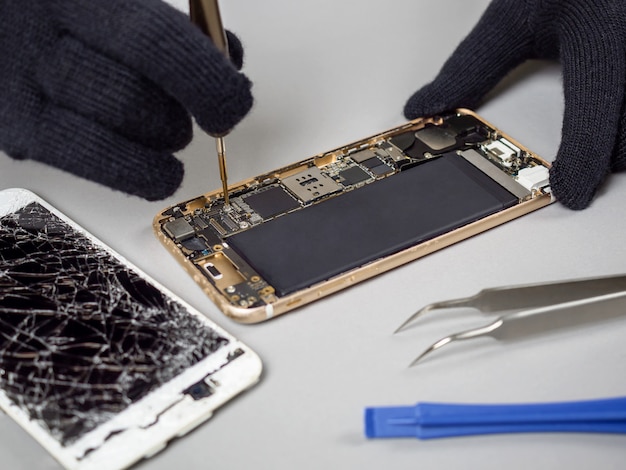 Photo technician repairing broken smartphone on desk