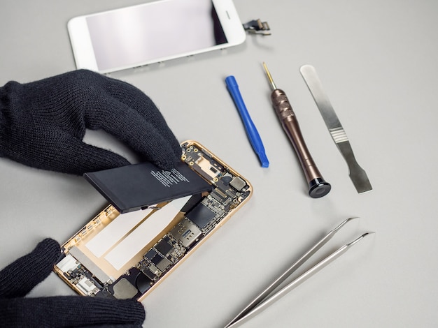 Technician repairing broken smartphone on desk