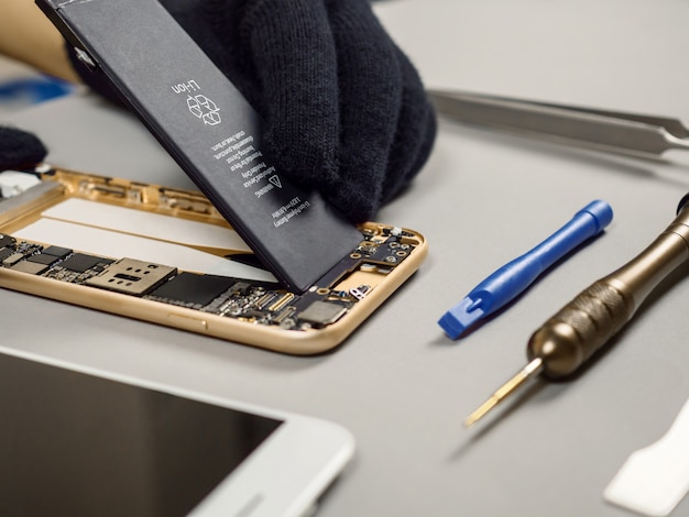 Technician repairing broken smartphone on desk