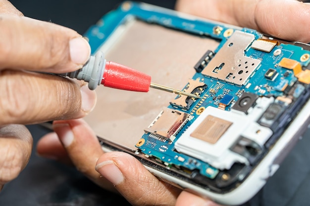 Technician repairing inside of mobile phone by soldering iron Integrated Circuit the concept of data hardware technology