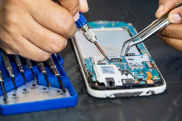 Photo technician repairing inside of mobile phone by soldering iron integrated circuit the concept of data hardware technology