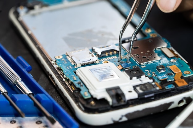 Technician repairing inside of mobile phone by soldering iron Integrated Circuit the concept of data hardware technology