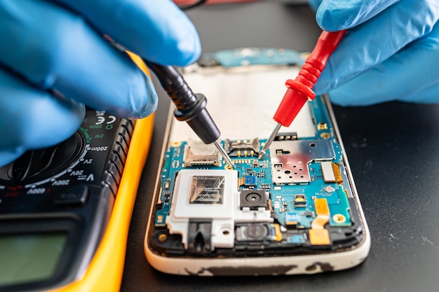 Technician repairing inside of mobile phone by soldering iron.