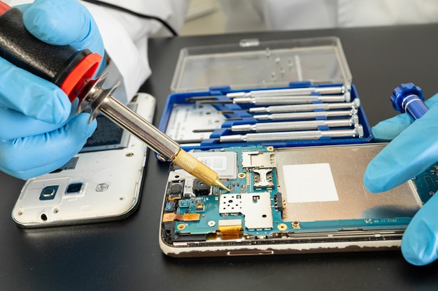 Technician repairing inside of mobile phone by soldering iron