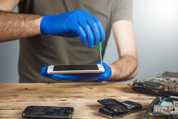 Technician repairing mobile phone at table