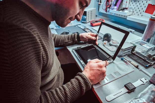 The technician repairs a broken tablet computer in a modern repair shop