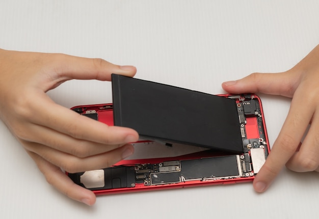 Photo technician replaces the battery of a cell phone or smartphone.